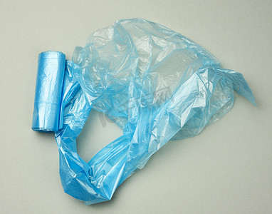 透明灰色背景摄影照片_灰色背景中用于垃圾箱的扭曲蓝色塑料袋