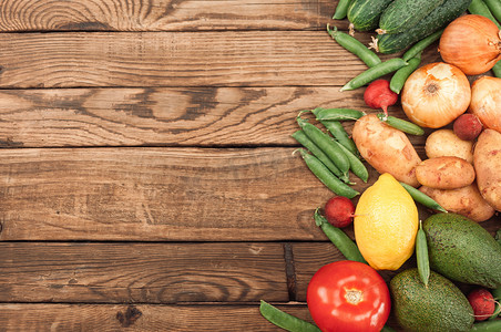 Flexitana 饮食概念。由各种新鲜有机蔬菜和水果组成。文本位置。黄瓜、西红柿、萝卜、鳄梨、豌豆、土豆、柠檬、洋葱。深色木质背景上的食物。
