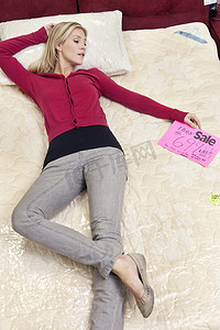 年轻女子躺在家具店的新床垫上