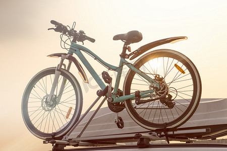 自行车和汽车后备箱紧靠天空背景。