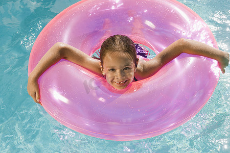 池中粉红色浮动管内的女孩