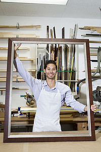 一个快乐的年轻工匠在车间里拿着大框架的肖像