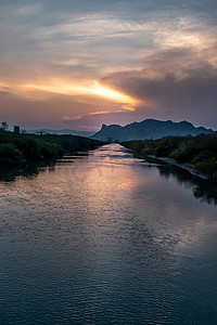 当太阳落在山后时，湖的傍晚景色很美，给夜空增添了戏剧性的金色光芒，反射在水中。