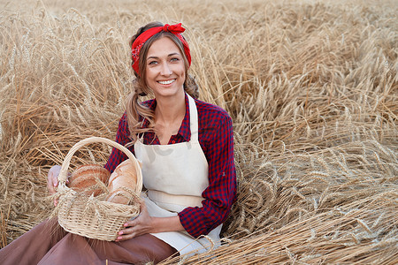 坐在麦田里的女农民拿着柳条筐面包产品的女面包师