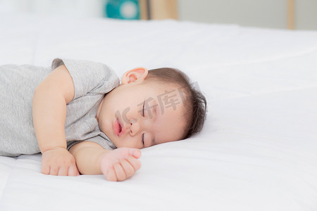 睡在家里卧室床上的亚洲小女婴的肖像，新生儿在舒适和放松的情况下打盹，睡前的婴儿纯真，快乐的幼儿可爱，孩子的成长和情感，在室内。