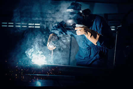 焊接火焰摄影照片_技术焊工是在装配车间进行钢材焊接，安全设备中的焊工结构是在工厂装配生产线上焊接金属。