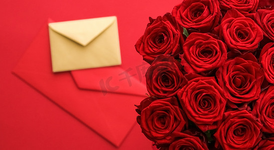 送玫瑰摄影照片_情人节的情书和送花服务、豪华的红玫瑰花束和红色背景的卡片信封