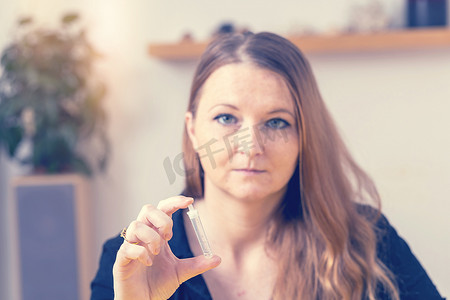 女人正在展示装有自检套件溶液的试管。