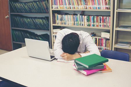 年轻的学生在图书馆看书睡得很累。