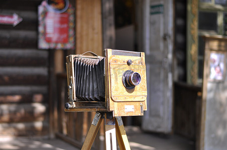 在一个旧木屋的背景上的三脚架上的老式相机。
