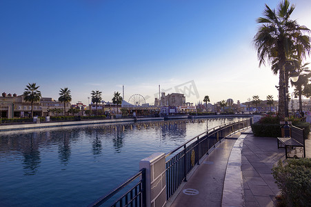 阿联酋迪拜 — 2020 年 12 月 16 日，在阿联酋迪拜地球村的傍晚日落时间，公园娱乐中心的国家馆和运河以及游船的美丽景色。