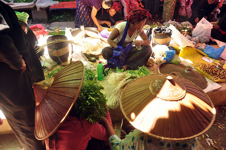 缅甸因勒 — 2015 年 11 月 29 日：阳光下的绿色当地湖泊市场，当地市场上的少数民族贫困亚洲部落人和天然商品
