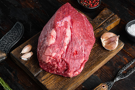 生大理石牛肉，在木切板上，在旧的深色木桌背景上