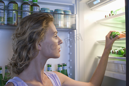 在冰箱里摄影照片_在冰箱里找食物的年轻女人