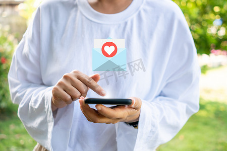 女人手使用智能手机，手机屏幕上会弹出电子邮件接收通知图标。