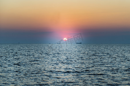 蓝色大气摄影照片_美丽的夕阳在平静的海面与蓝色和橙色的发光天空。