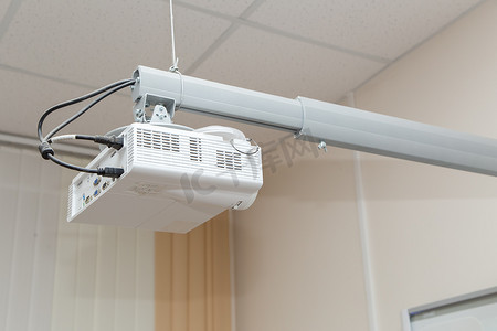 白色视频投影仪悬挂在可调节的天花板支架上。