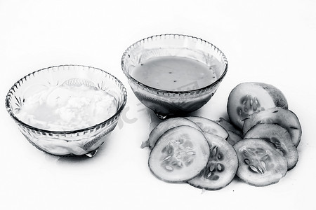 在白色上隔离的黄瓜面膜，即黄瓜果肉与 dahi 或酸奶在玻璃碗中充分混合，所有原料都存在于表面。用于治疗易长粉刺的皮肤。