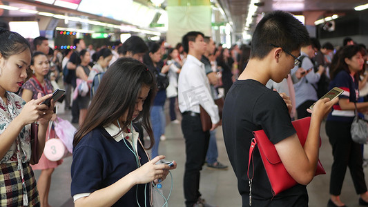 泰国曼谷-2018 年 12 月 18 日：泰国曼谷 BTS 轻轨站的乘客，每个人在等待 BTS 轻轨时都低头看着智能手机