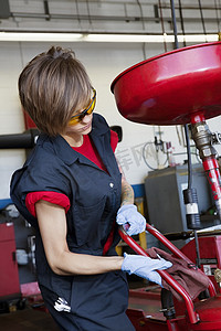 汽车修理店摄影照片_在焊接设备上工作的年轻女技工