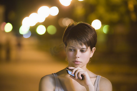 短发少女摄影照片_十几岁的女孩站在街上用手机思考