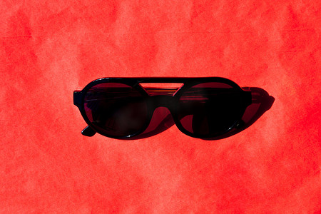 Fashionabls 黑色太阳镜与红色背景上的影子。
