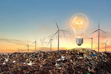 风力涡轮机和电灯泡在垃圾山顶部有戏剧性的日落天空背景。