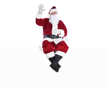 穿着传统圣诞老人套装的老人坐在白色的墙上，一只手举在空中，另一只手放在肚子上，闭着眼睛。
