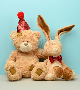 长耳朵摄影照片_戴帽子的泰迪熊和长耳朵的可爱泰迪兔，脖子上系着一只红蝴蝶