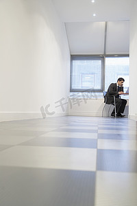 地面头发摄影照片_坐在空房间地面视图中使用笔记本电脑的商人