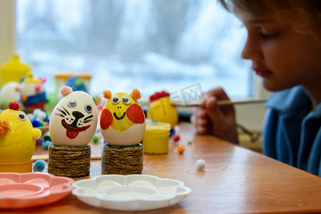 前景是装饰过的儿童复活节彩蛋，背景是一个孩子正在画彩蛋