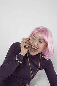 戴着粉色假发的年轻女人对着手机笑