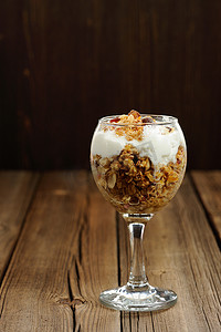 饼干酸奶摄影照片_玻璃杯中的格兰诺拉麦片和木质背景的酸奶