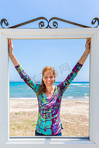 靠近蓝色大海和海滩的窗户里快乐的荷兰女人