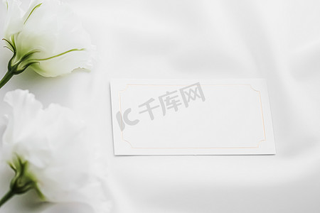 布局平面图摄影照片_婚礼请柬或礼品卡和丝绸织物上的白玫瑰花作为新娘平面背景、空白纸和假日品牌、平面布局设计