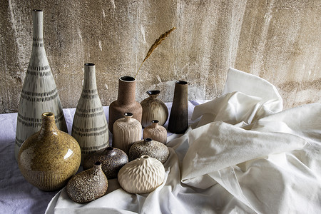白色桌子上手工制作的各种不同的陶瓷花瓶。