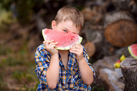 男孩拿着一片西瓜，从后面往外看。