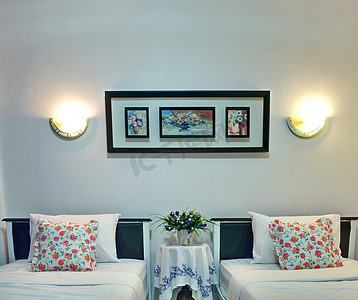 枕套摄影照片_豪华的双床卧室配有白色床单和花卉枕套。