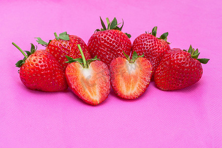 表面布满种子的草莓甜红果粉红色织物质地的一组特写红莓心形水果