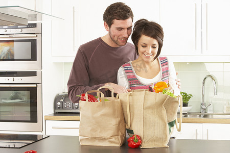 年轻夫妇在现代厨房开箱购物
