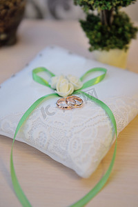 带绿色蝴蝶结垫子上的结婚戒指