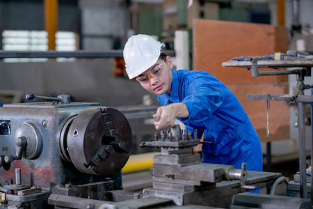 工厂其他摄影照片_亚洲工厂穿着蓝色制服和其他保护措施，包括安全帽，检查机器的工作功能。