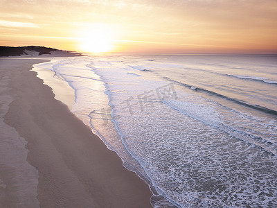 日出在海洋和空荡荡的海滩上的航拍