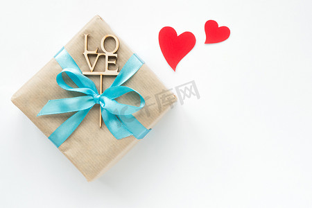 在包装纸包裹的礼物盒与蓝丝带和红色心脏在白色背景。