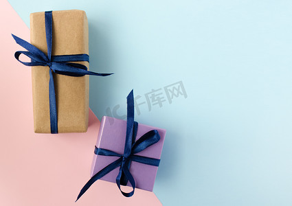 动态问好带字摄影照片_两个带蓝丝带的彩色礼品盒和蓝粉色背景上的蝴蝶结，带复制空间。