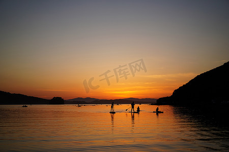 美丽的夕阳与 SUP 冲浪者的剪影。