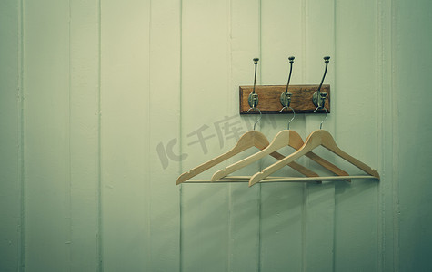 棕色木衣架挂在白色木墙背景的金属钩上。