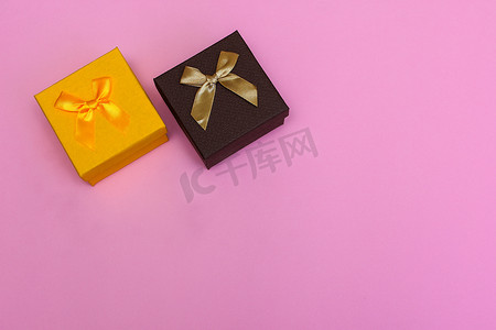两个圣诞亮丽的礼盒，在粉红色的背景上用丝带系着蝴蝶结，上面有铭文的地方。