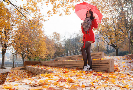 穿着红色外套、撑着雨伞站在巷子里的小女孩