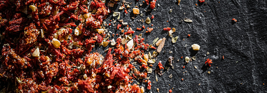 干番茄和辣椒特写在豪华的石头背景上，作为平铺、干食品香料和配方成分